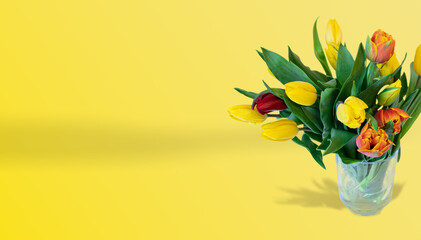 Naklejka premium bukiet tulipanów w szklanym wazonie na żółtym tle