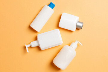 Set of White Cosmetic containers isolated on colored background, top view with copy space. Group of plastic bodycare bottle containers with empty space for you design