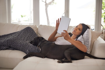 Woman, tablet and dog in home for relax with typing email, communication and online movie in living...