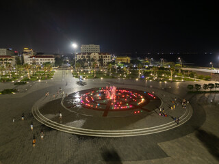 People enjoying the beautiful color display of the singing fountain at night in a public park in Tuy Hoa, Vietnam