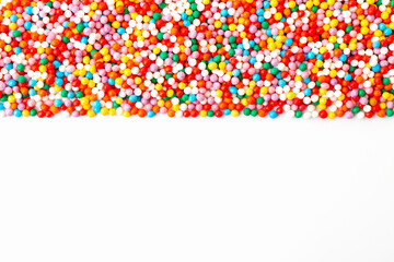Colorful confectionery sprinkles border on white background. Copy space for text. Top view