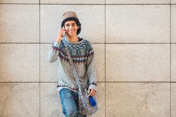 relaxed urban young man on the street wall talking on the phone