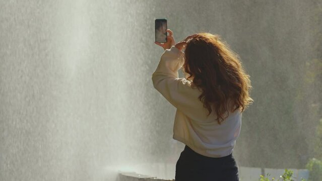Female taking picture for blog nature waterfall background