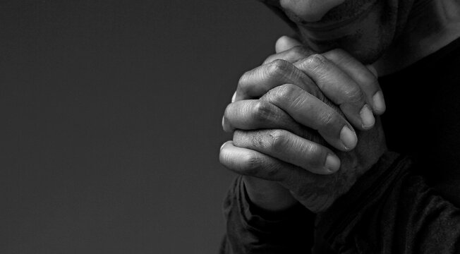 black man praying to god with hands together Caribbean man praying on black background with people stock photos stock photo	