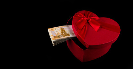 A 100 Russian ruble banknote and a gift box in the shape of a human heart