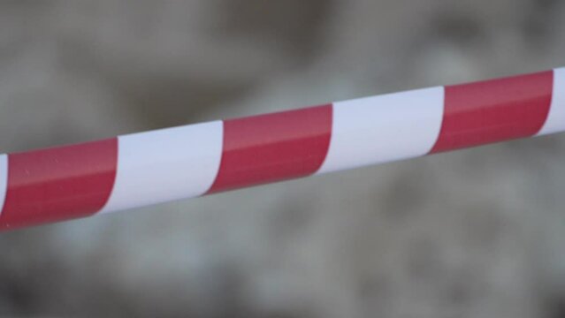 Red and white warning tape swinging in the wind. Protection sign. Don't cross the line. Red White caution tape pole fencing is protects for No entry. Backdrop without people, empty street.