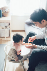 Obraz premium 赤ちゃんに離乳食を食べさせるお父さん