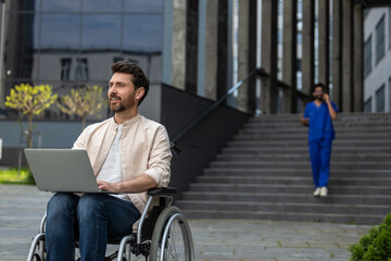 Disabled self-employed man working on laptop while sitting in wheelchair in hospital yard