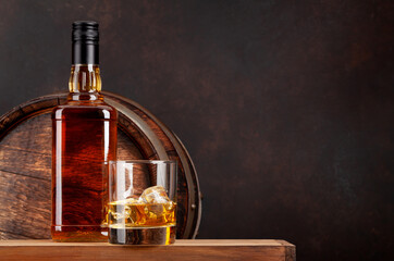 Scotch whiskey bottle, glass and old barrel