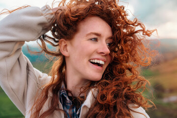 Close up of portraut of amazing redhead woman reaching the destination and enjoying mountains...