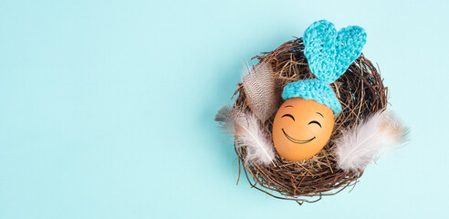 Easter bunny or rabbit egg  in a bird nest, crocheted ears and feathers, spring holiday, blue color
