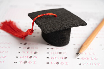 Graduation gap hat and pencil on answer sheet background, Education study testing learning teach...
