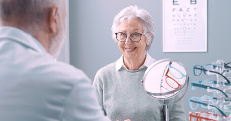 Senior woman wearing her new glasses at the optician shop