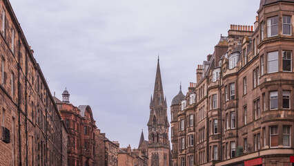 The Edinburgh cityscape is graced by the spire of Barclay Viewforth Church, rising eloquently above the charming facades of traditional sandstone tenements under a soft, overcast sky