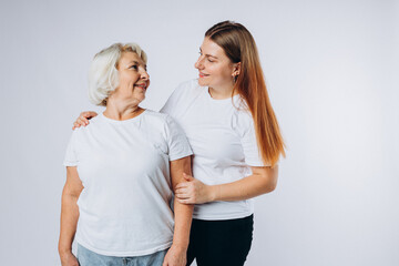 Head shot portrait of happy senior 60s mother and young grownup daughter over white studio...