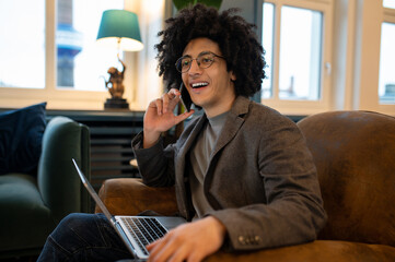 Young smiling curly-haired man spending time online