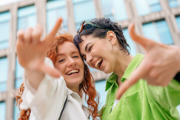 smiling young women girlfriends having a fun time together, talking and using phones, shopping outdoor in an urban city. People, communication, friendship and lifestyle concept