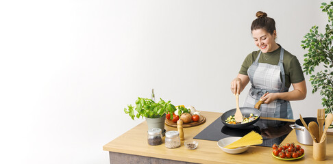 Happy woman cooking vegetables in a pan