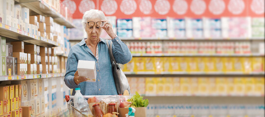 Senior woman with vision problems reading information on a product package at the supermarket