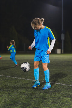 vertical shot of a Caucasian football player little girl with a ball at the practice. High quality photo