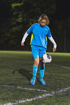 school-age Caucasian girl with blue uniform practicing football in a stadium at night. High quality photo