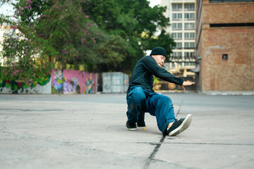 Young handsome male dancer in stylish clothes showing hip hop performance on the street