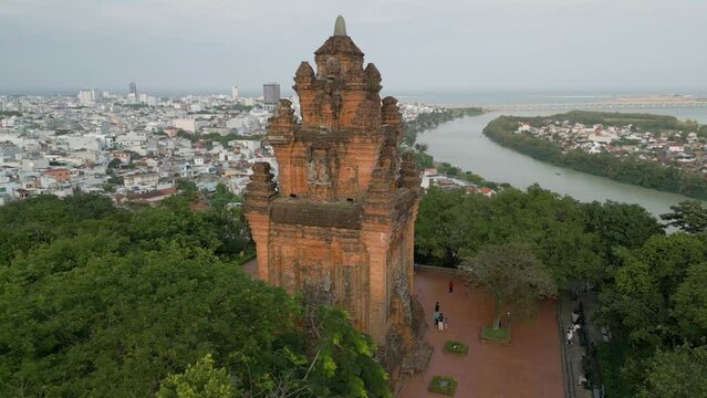 Aerial drone shot of the stunning historical Nhan Temple, an architectural cultural heritage of the Cham people, elevated on a green hillside above the city of Tuy Hoa, Vietnam
