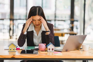 Businesswoman appears stressed and concerned while working on financial matters at her office desk,...