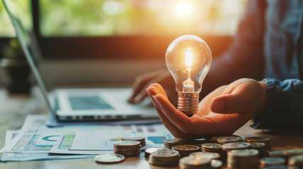business accounting with saving money with hand holding lightbulb concept financial background - obrazy, fototapety, plakaty