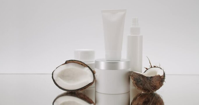 White Bottle and tubes with Tropical fruit coconut for cosmetics on a white background in studio. Cosmetics oils based on natural ingredients, scrub, tonic, body care. Glossy cosmetic jar with cream.