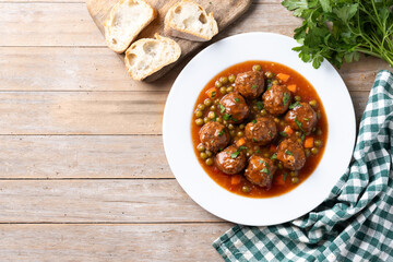 Meatballs, green peas and carrot with tomato sauce on wooden table. Top view. Copy space