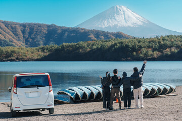 tourists enjoy with Fuji Mountain at Lake Saiko, happy friends group travel Mount Fuji and road...