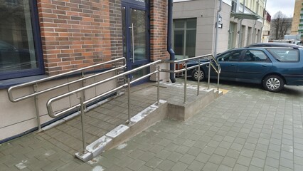 To enable people with disabilities to enter the building, a concrete and tile sloping ramp with...