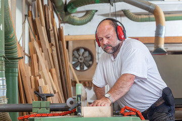 Tischler in seiner Werkstatt arbeitet an der Hobelmaschine - 756348398