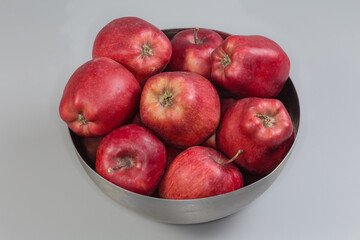 Fototapeta na wymiar Red apples in stainless steel bowl on a gray background