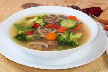 Serving of vegetable soup with mushrooms on rustic table