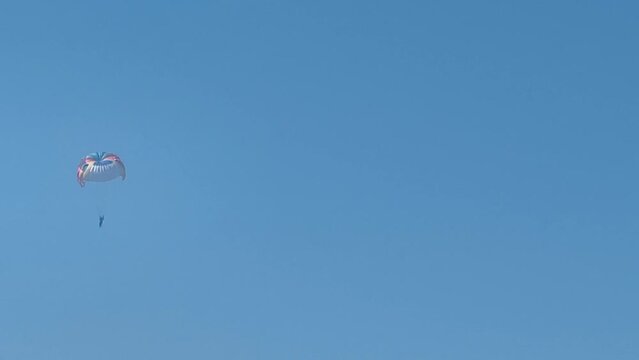 Parasailing above the sea, colourful parachute soaring in clear blue sky