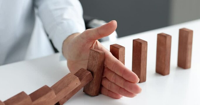 Risk and strategy in business is hand stopping the fall of wooden block. Prevention and development of fall in stability