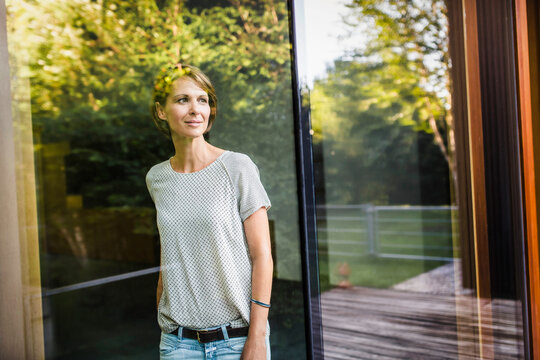 &nbsp;Frau nachdenklich am Fenster Blick nach draussen, Spiegelungen Laubbaum, Bayern, Deutschland