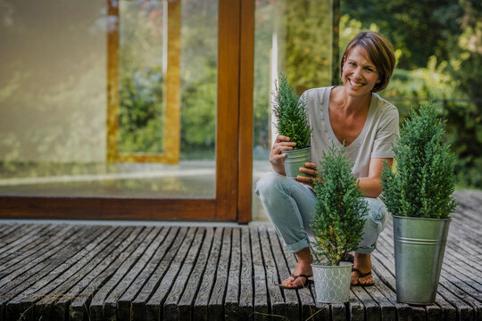 gl&uuml;ckliche Frau mit Blumentopf vor einer neuen Immobilie, Bayern, Deutschland