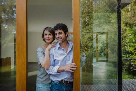 gl&uuml;ckliches Paar schaut aus dem Fenster einer neuen Immobilie, Bayern, Deutschland