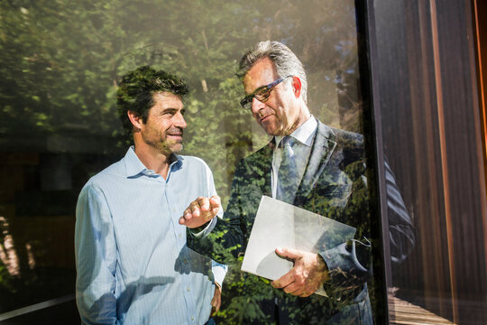 best ager Mann mit Immobilienmakler schauen Vertragsunterlagen an einer neuen Immobilie, Blick durch ein Fenster, Bayern, Deutschland