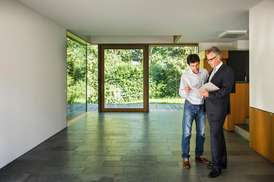 Mann mit Immobilienmakler in einer neuen Immobilie, Bayern, Deutschland