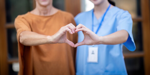 Nurse or caregiver and elderly woman support, healthcare service and health portrait at home. Medical physiotherapy, make a heart shape with your hands together in home
