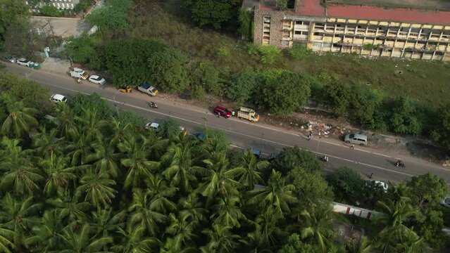 Aerial shot of red car in the middle of the street with coconut trees nearby
