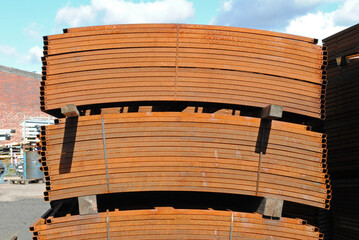 Stack of Curved Rusty Steel Barriers in Industrial Yard on Sunny Day in Close Up 