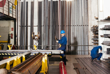Obraz premium Male workers working with hydraulic cranes in metal beams workshop
