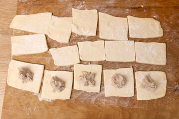 Pieces of meat are laid out on the puff pastry. Preparation of meat pies from puff pastry.