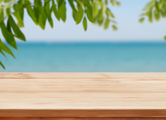 Wooden table with blurred the beach and green plant
