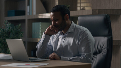 Concerned Indian man American businessman at table take off glasses thinking problem solution...